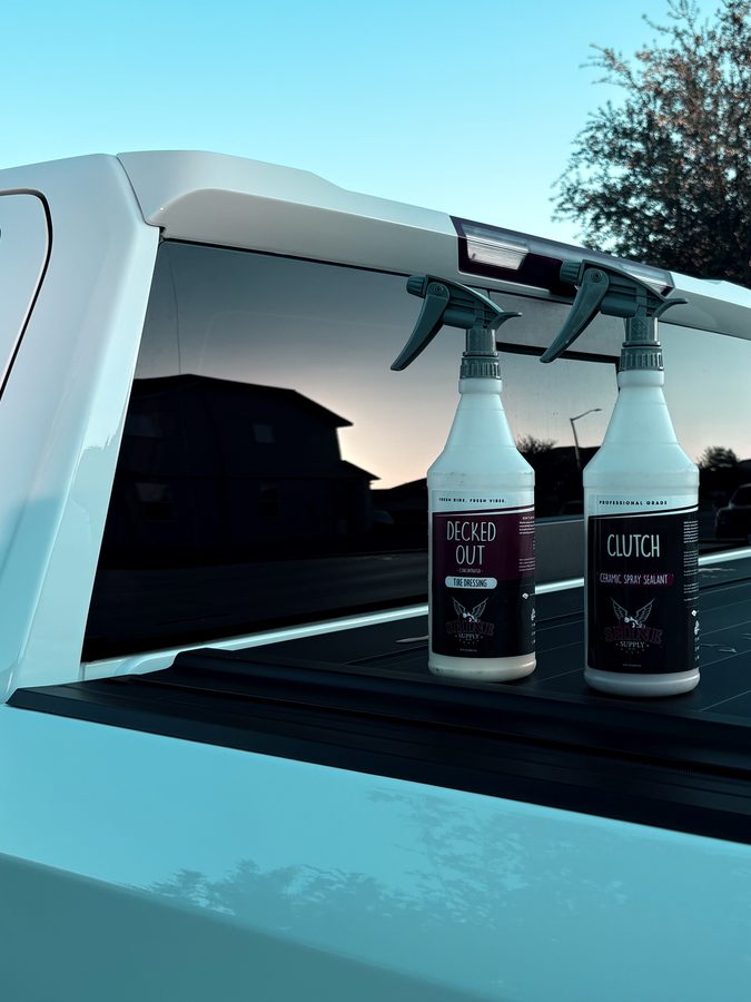 Ceramic spray sealant and tire dressing bottles on a truck tonneau cover at dusk